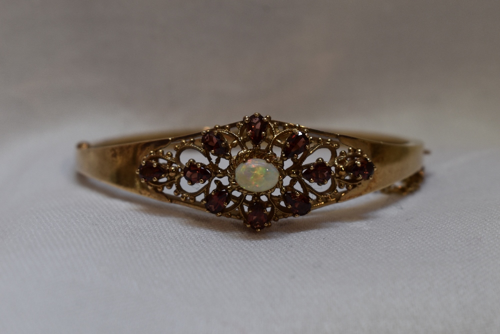 A 9ct gold hinged bangle having an opal and tourmaline set open panel and concealed clasp
