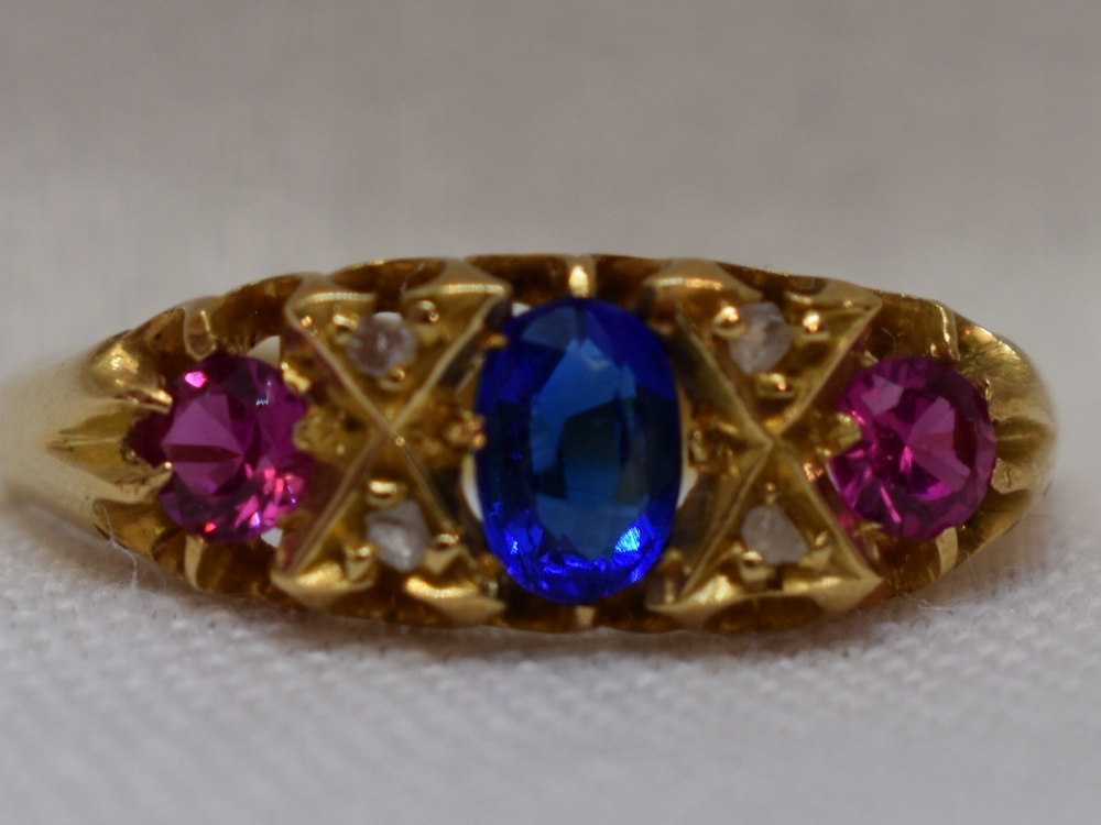 A lady's dress ring having a sapphire style stone flanked by two rubies interspersed by diamond