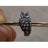 An owl brooch having diamond chip decoration and ruby cabouchon eyes on a rose metal bar stamped