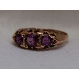 A lady's dress ring having a trio of amethysts in a gallery mount on a 9ct rose gold loop, size M