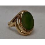 A lady's dress ring having a Canadian jade oval panel in a stepped collared mount on a yellow
