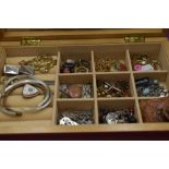 A wooden jewellery box containing a selection of costume jewellery including rosary beads, earrings,