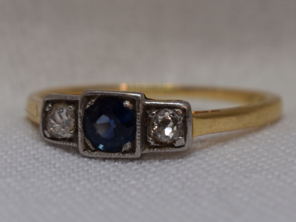 A lady's dress ring having a central sapphire flanked by two diamonds each approx 0.064ct in an