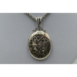 An HM silver locket having engraved scroll decoration on a snake link chain