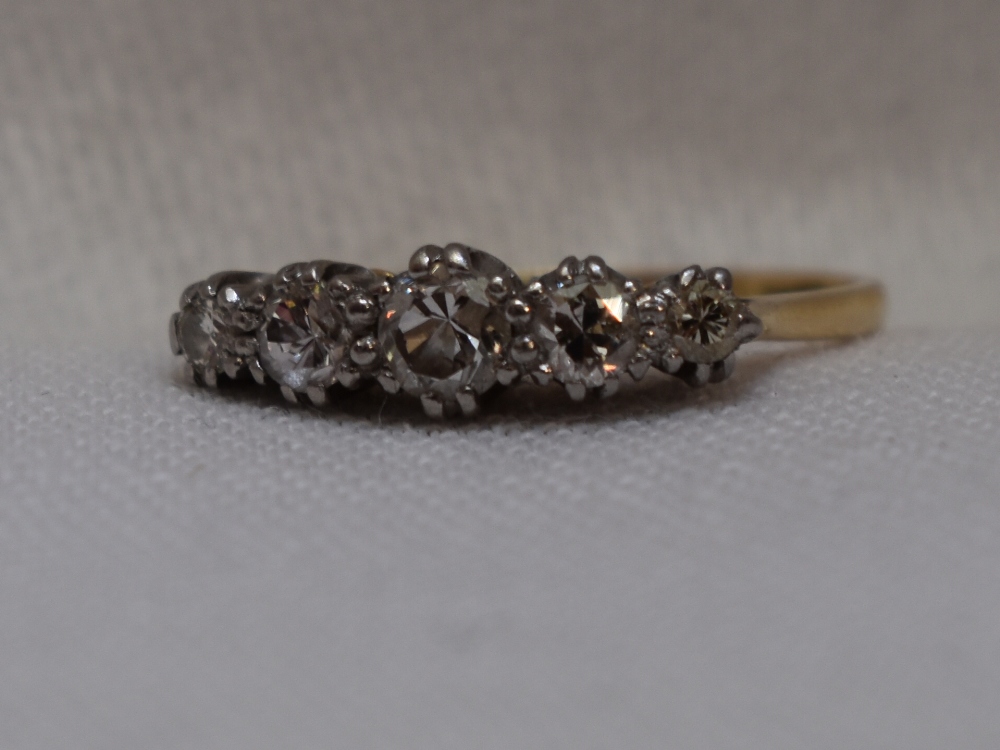 A lady's dress ring having five graduated diamonds in a claw set raised mount on a yellow metal loop