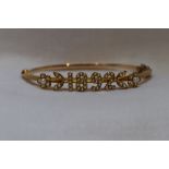 A Victorian yellow metal hinged bangle having a seed pearl applique date panel of 1892, no marks,