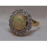 A lady's dress ring having a central opal cabouchon within a pave diamond surround, total approx 0.