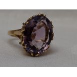 A lady's dress ring having a large oval amethyst in a raised double claw basket mount on a 9ct
