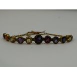 A Victorian graduated multi gem set articulated bracelet with yellow metal chain and barrel clasp