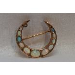 A graduated opal set crescent brooch having diamond chip decoration on a yellow metal gallery mount,