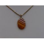 A striped orange agate pendant in a yellow metal mount on a 9ct gold snake link chain, approx 16'