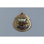 A 9ct gold medallion having enamelled Barrow in Furness coat of arms to front and presentation