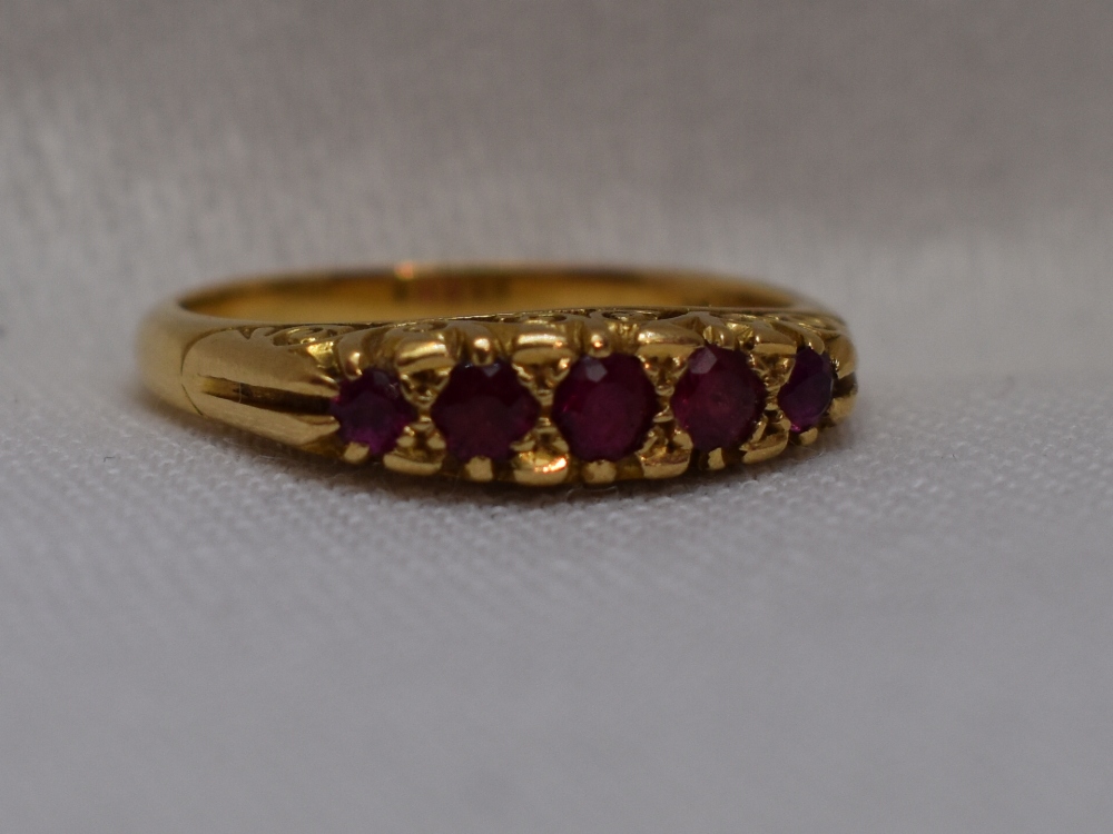 A lady's dress ring having five graduated rubies in a gallery mount on a yellow metal loop stamped