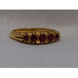 A lady's dress ring having five graduated rubies in a gallery mount on a yellow metal loop stamped