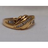 A lady's dress ring having channel set baguette cut diamonds in a moulded wave style setting on a