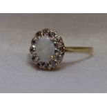 A lady's dress ring having an oval opal and diamond chip cluster in an illusionary mount on a 9ct