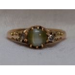 A lady's dress ring having a green cabouchon stone (possibly green sapphire) flanked by a diamond