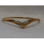 An 18ct gold hinged bangle of wish bone form having diamond chip decoration