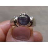 A lady's dress ring of Artisan form having a star sapphire cabochon in a collared mount to shaped