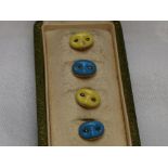 A cased set of four French gold and enamel collar studs in the form of yellow and blue masks with