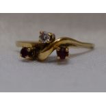 A lady's dress ring having a trio of diamond and rubies in a stylised mount on an 18ct gold loop,