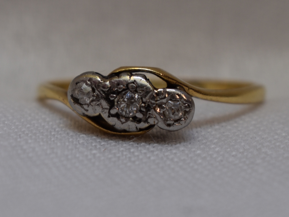 A lady's dress ring having a trilogy of diamond chips in an illusionary mount to cross over