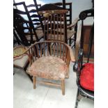 An early 19th century elm kitchen armchair, having comb spindle back with later cushion seat and