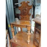 A Victorian golden oak hall chair having shield back with solid seat and coronet and wrythen legs