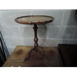 A 20th century stained frame wine table having circular pie crust top, on pedestal and triple