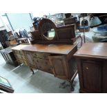 A late Victorian mahogany sideboard having raised circular mirror back on central drawers, flanked