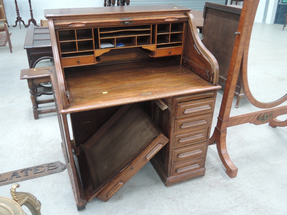 An early 20th Century oak roll top desk having tambour shutter and single pedestal drawers,