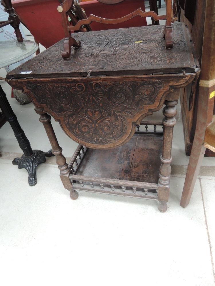 A late 19th century dark oak occasional table having extensive foliate carved drop flap top, on