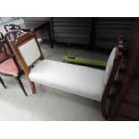 A late Victorian golden oak window seat having Aesthetic decoration and later cream upholstery,