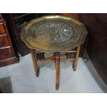 An early 20th century Eastern brass tray top occasional table on treen folding base, width approx.