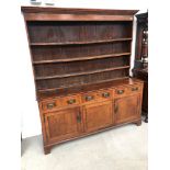 A 19th Century oak dresser having shelved delft rack over frieze drawers with triple cupboard under,