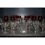 An assortment of crystal glasses and a set of eight red glasses.