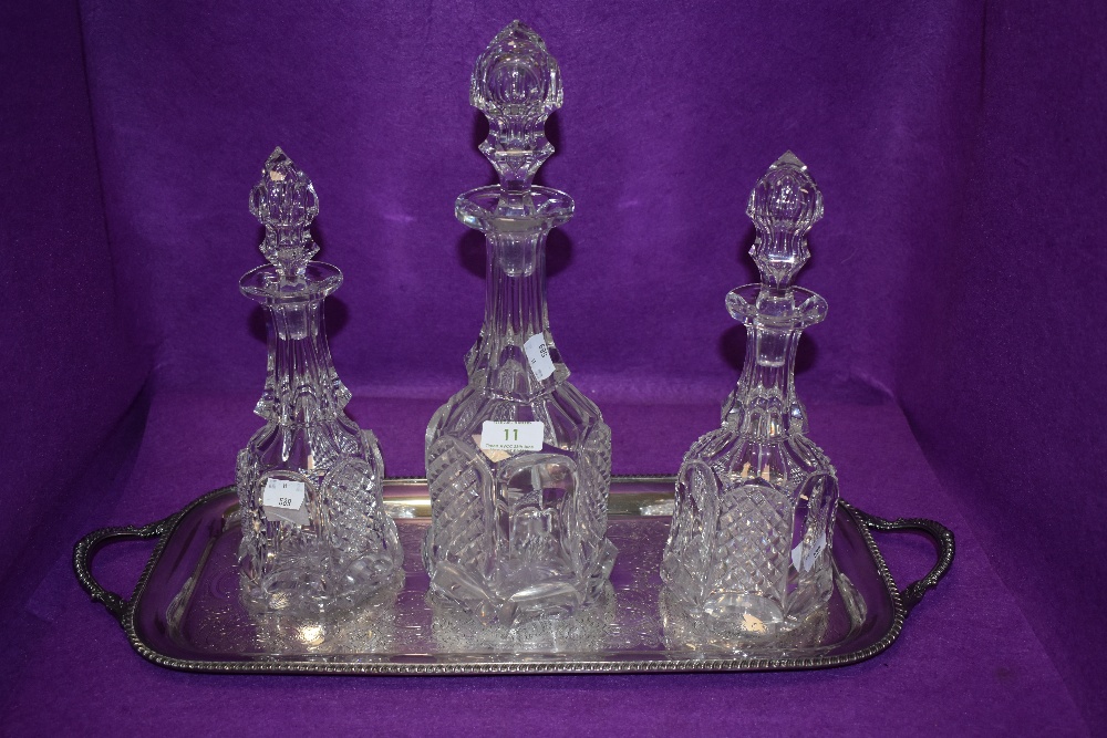 Three cut glass decanters on a metal tray.