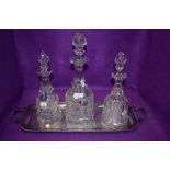 Three cut glass decanters on a metal tray.