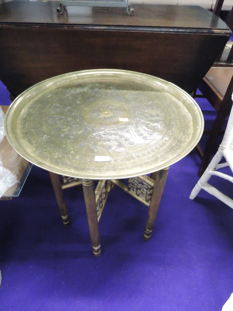 An Eastern style brass tray table, the folding frame being of spindle form, with gold spray