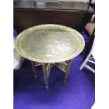 An Eastern style brass tray table, the folding frame being of spindle form, with gold spray