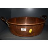 A large vintage copper pan having handles to sides.