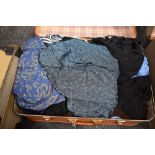 A vintage suitcase containing a collection amount of ladies modern and retro blouses and similar.