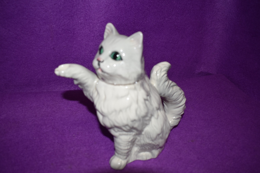 A quirky Beswick tea pot in the form of a white cat, the tail being the handle and the paw, its