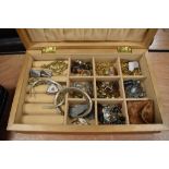 A wooden jewellery box containing a selection of costume jewellery including rosary beads, earrings,
