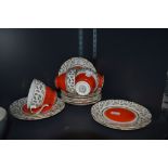 A vibrant collection of cups, saucers and side plates, having block orange centres to the plates and