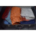 A suitcase containing various vintage materials including lace. Different colours and styles.