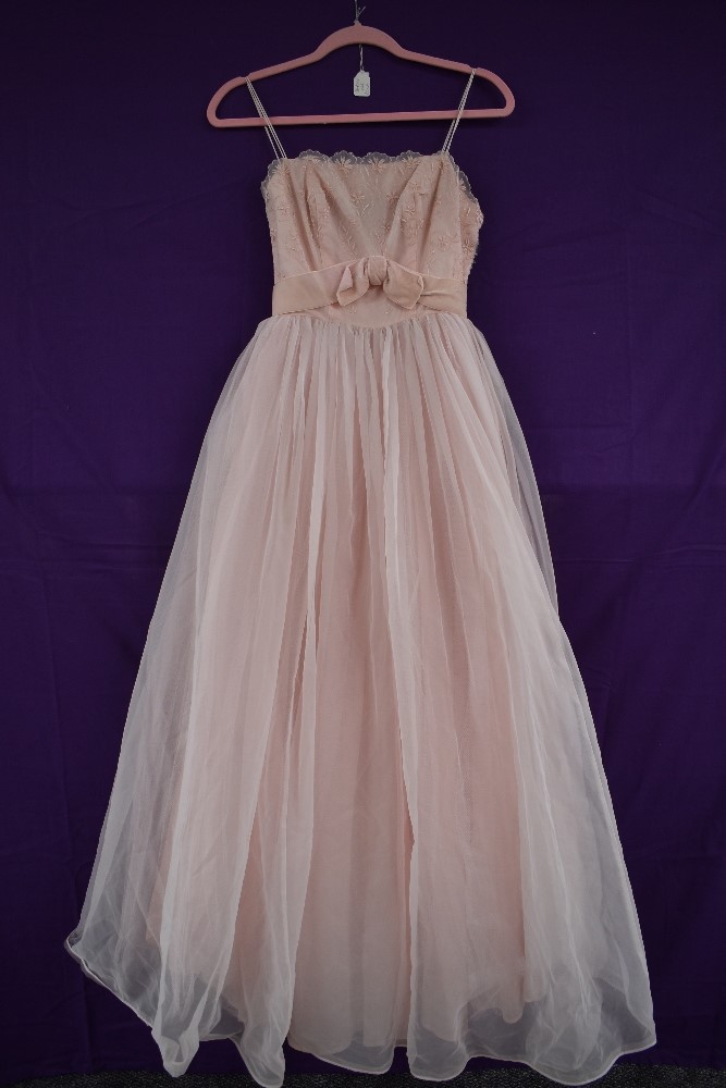 A vintage 1950s pale pink evening gown,having layered skirt and tiered detailing to back, boned