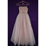 A vintage 1950s pale pink evening gown,having layered skirt and tiered detailing to back, boned