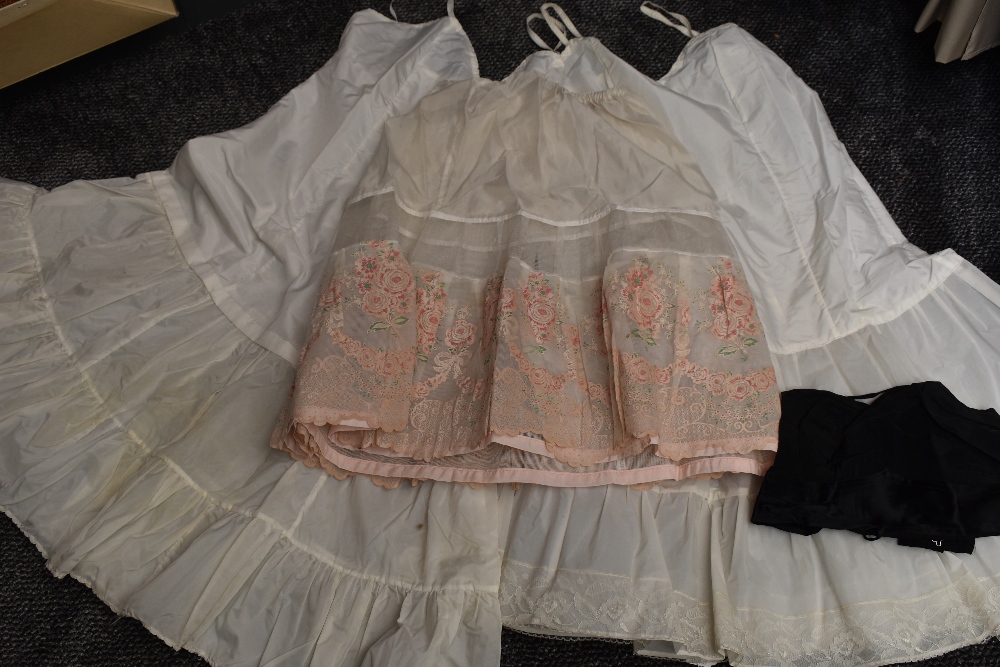 Three vintage petticoats, one of which has a flocked rose pattern to the scalloped hem, also