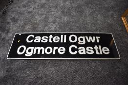 A wooden sign, Castell Ogwr Ogmore Castle, silver lettering and border on black background, 59 x